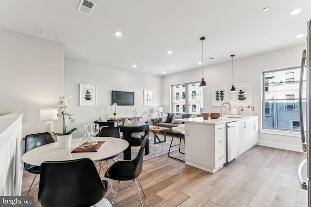 dining space with sink, light hardwood / wood-style flooring, and a wealth of natural light