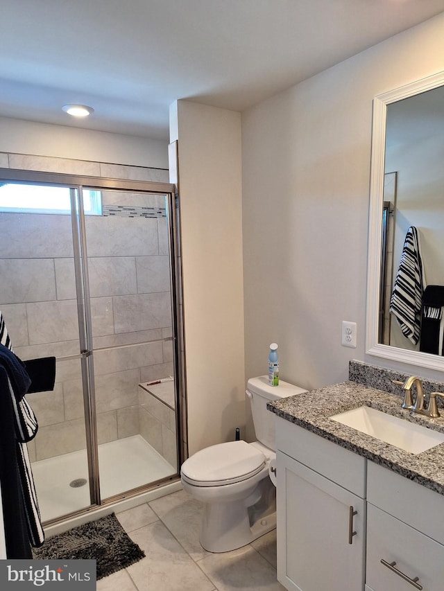 bathroom featuring toilet, walk in shower, vanity, and tile patterned flooring