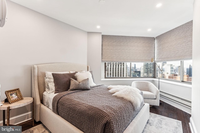 bedroom featuring a baseboard heating unit and hardwood / wood-style floors