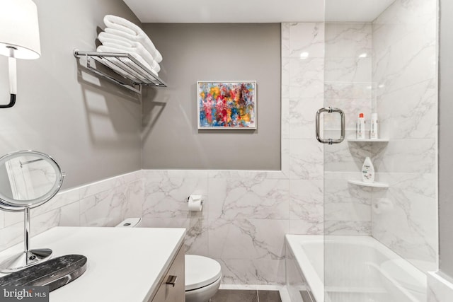 bathroom featuring vanity, tile walls, a tub, and toilet