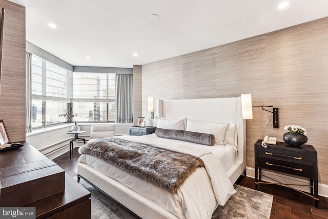 bedroom with dark hardwood / wood-style flooring and a baseboard heating unit