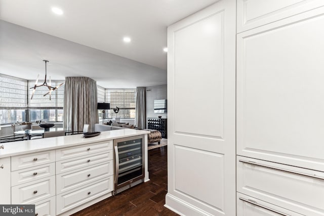 kitchen with pendant lighting, dark hardwood / wood-style floors, white cabinets, beverage cooler, and a chandelier