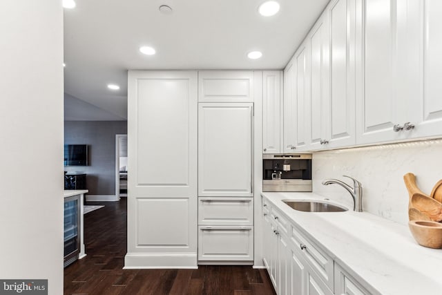 kitchen featuring sink, backsplash, white cabinets, dark hardwood / wood-style flooring, and light stone countertops