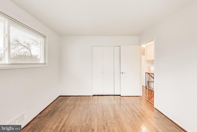 unfurnished bedroom featuring a closet, baseboards, and wood finished floors