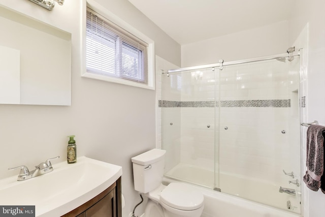 full bathroom featuring toilet, bath / shower combo with glass door, and vanity