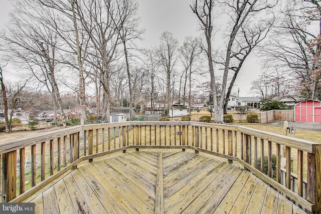 deck featuring a storage unit, an outdoor structure, a fenced backyard, and a residential view