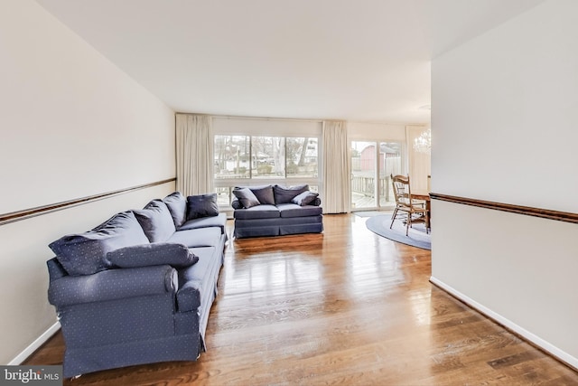 living area featuring an inviting chandelier, wood finished floors, and baseboards