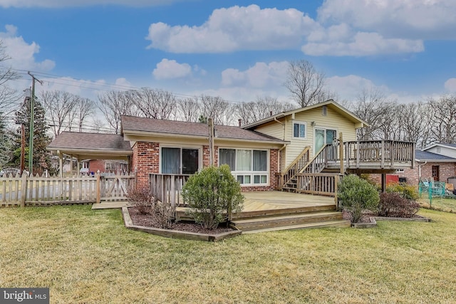 back of property with fence, a deck, a lawn, and brick siding