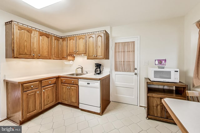 kitchen with white appliances, light countertops, a sink, and brown cabinetry