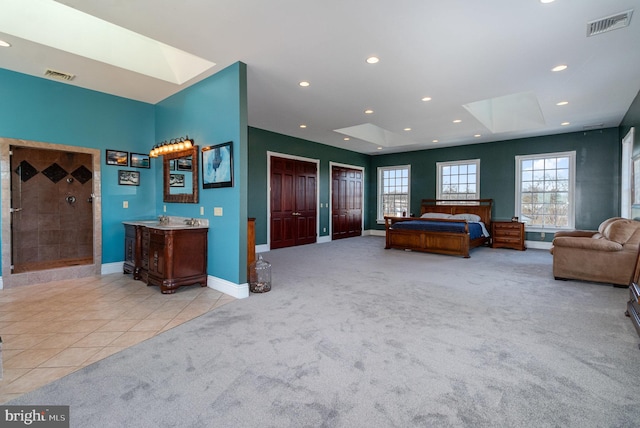 carpeted bedroom featuring a skylight and two closets