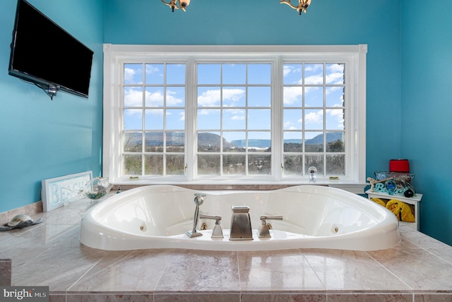 bathroom with a mountain view, plenty of natural light, and tiled bath