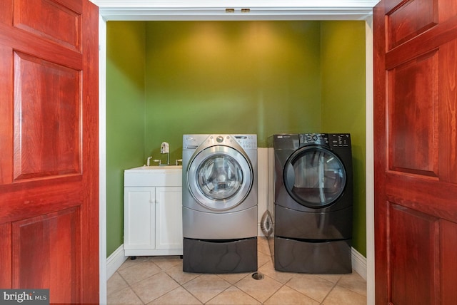 clothes washing area featuring cabinets, sink, washer and dryer, and light tile patterned floors