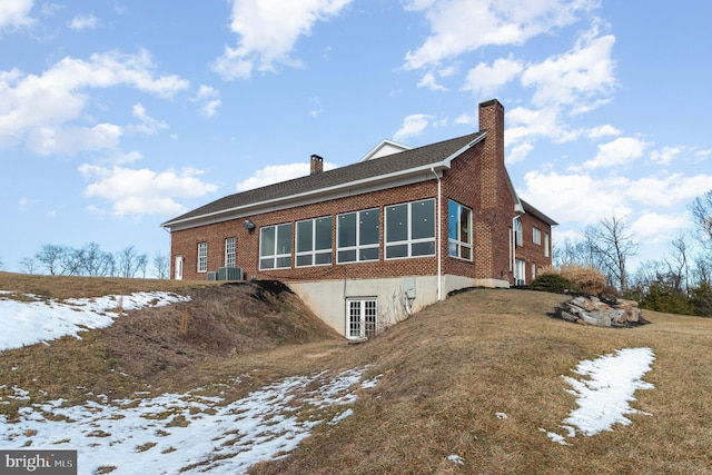 snow covered rear of property with central AC unit