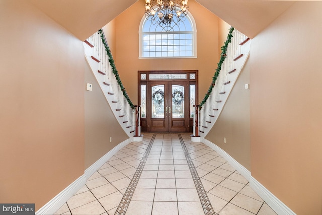 foyer entrance with an inviting chandelier, high vaulted ceiling, and light tile patterned floors