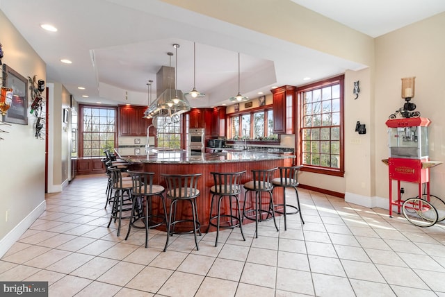 kitchen with light tile patterned flooring, a tray ceiling, pendant lighting, and dark stone counters