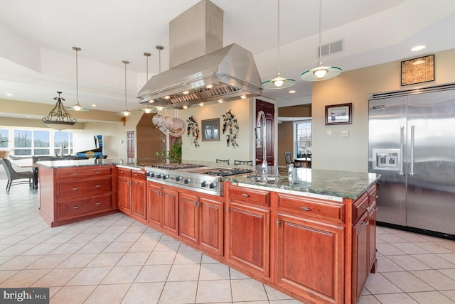 kitchen with hanging light fixtures, dark stone countertops, appliances with stainless steel finishes, and island range hood