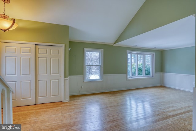 unfurnished bedroom featuring crown molding, vaulted ceiling, a closet, and light wood-type flooring