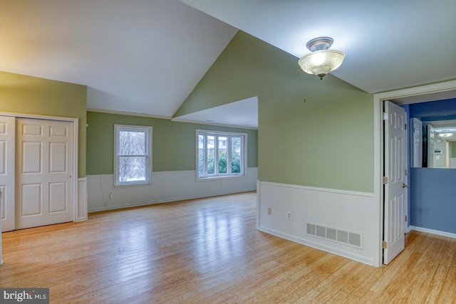 empty room with lofted ceiling and light wood-type flooring