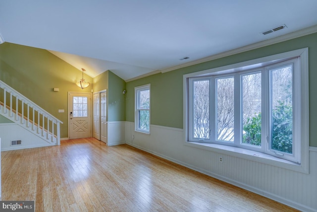 entrance foyer featuring crown molding, vaulted ceiling, and light wood-type flooring