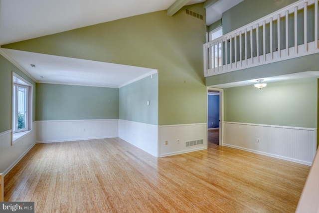 unfurnished room with light hardwood / wood-style flooring and lofted ceiling with beams