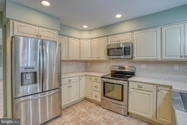 kitchen with light tile patterned flooring, stainless steel appliances, and decorative backsplash