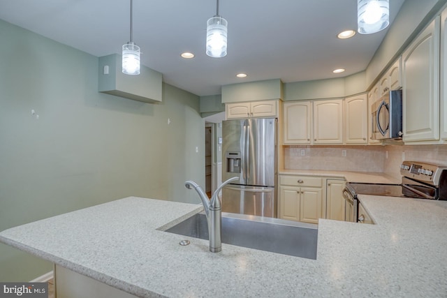 kitchen with sink, light stone counters, decorative light fixtures, appliances with stainless steel finishes, and backsplash