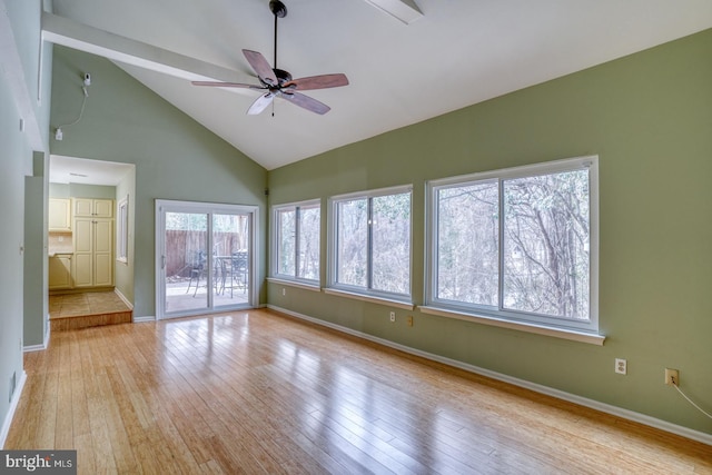 spare room with plenty of natural light, high vaulted ceiling, ceiling fan, and light hardwood / wood-style flooring