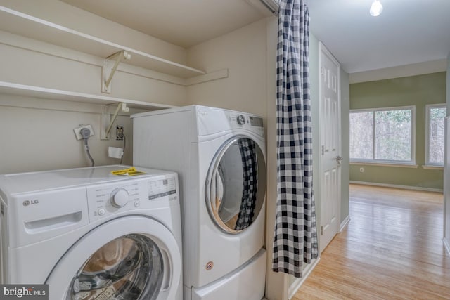 clothes washing area with light wood-type flooring and washer and clothes dryer