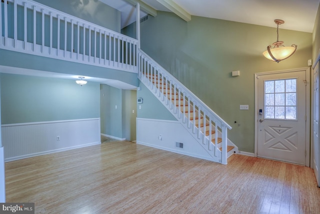 foyer entrance featuring beam ceiling, high vaulted ceiling, and light wood-type flooring