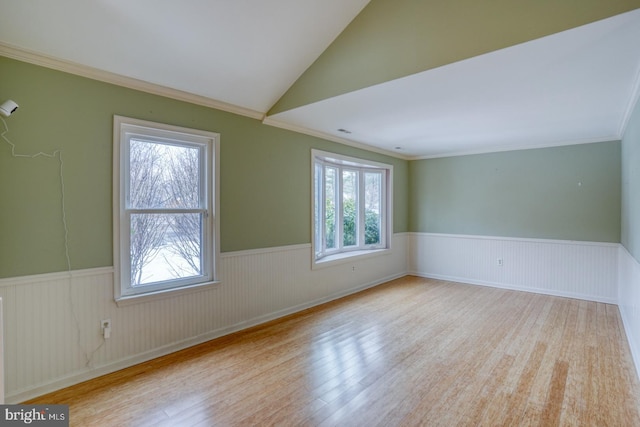 spare room featuring lofted ceiling, crown molding, and light hardwood / wood-style flooring