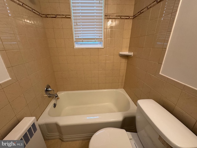 bathroom featuring toilet, radiator heating unit, washtub / shower combination, and tile walls