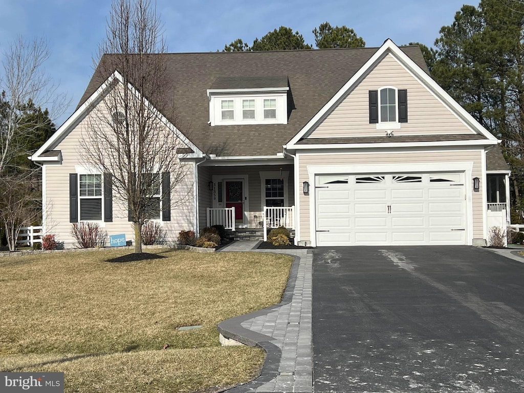 view of front of home featuring a garage, covered porch, and a front yard