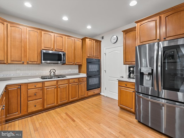 kitchen featuring appliances with stainless steel finishes, backsplash, and light hardwood / wood-style floors