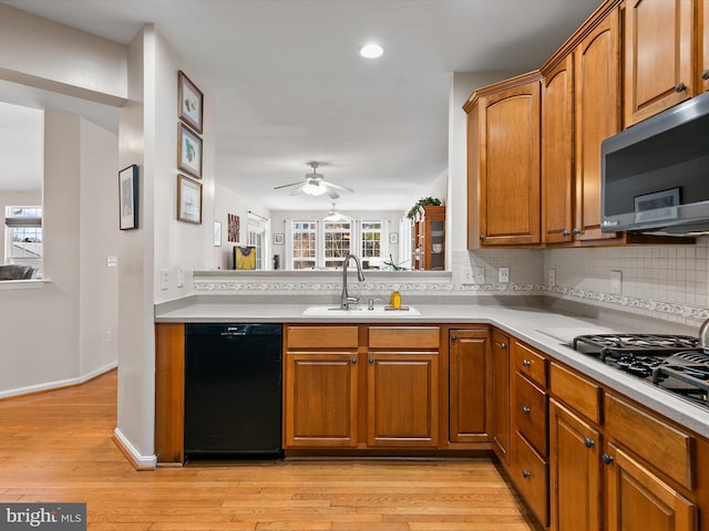 kitchen with sink, gas stovetop, dishwasher, light hardwood / wood-style floors, and decorative backsplash