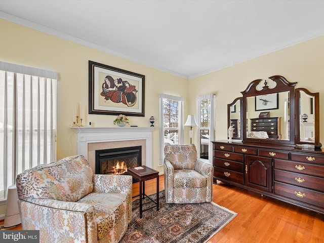 sitting room with ornamental molding and light wood-type flooring