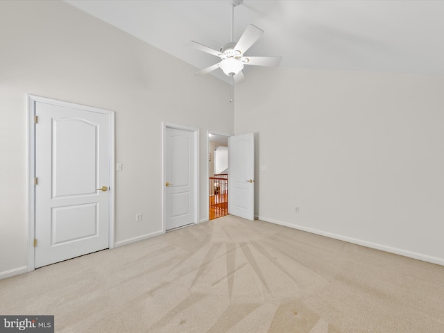 unfurnished bedroom featuring ceiling fan, light carpet, and high vaulted ceiling