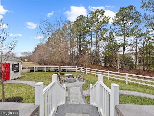 view of yard featuring a rural view, a shed, and an outdoor fire pit