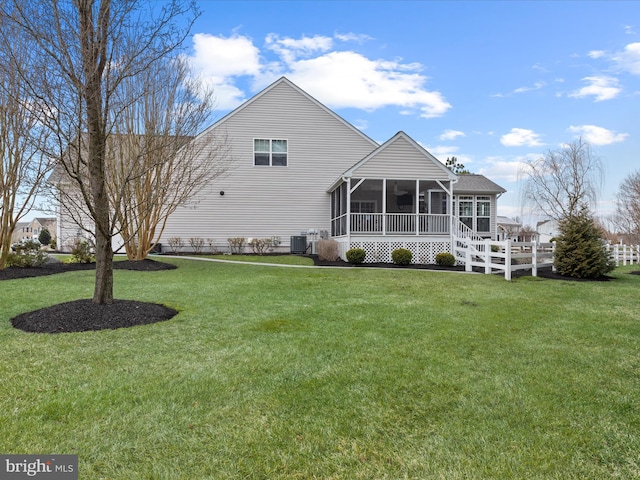 back of property with a sunroom, a yard, and central AC unit