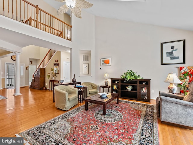 living room with ceiling fan, hardwood / wood-style floors, a high ceiling, and ornate columns