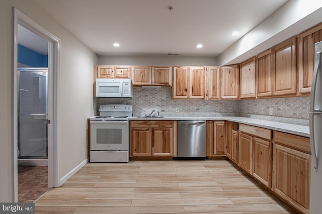 kitchen featuring backsplash, white appliances, light hardwood / wood-style flooring, and sink