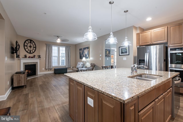 kitchen featuring hanging light fixtures, appliances with stainless steel finishes, sink, and a center island with sink