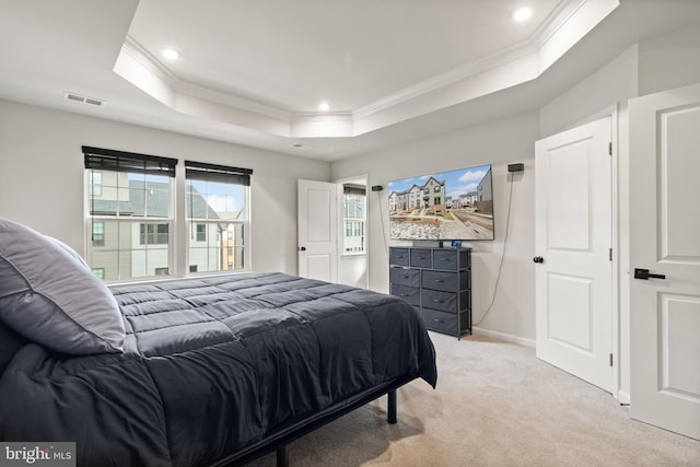 bedroom featuring ornamental molding, light colored carpet, and a tray ceiling