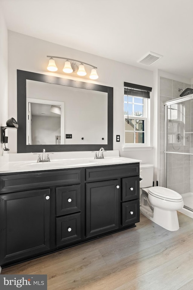 bathroom with hardwood / wood-style flooring, an enclosed shower, vanity, and toilet