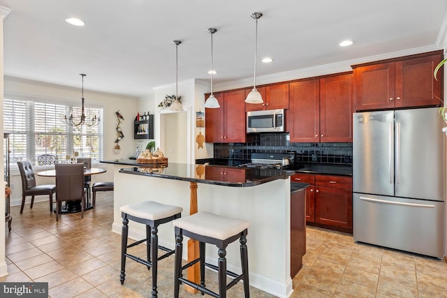 kitchen with a kitchen island, appliances with stainless steel finishes, backsplash, a kitchen breakfast bar, and hanging light fixtures