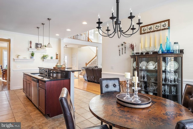 dining space with sink, ornamental molding, a chandelier, and light tile patterned flooring