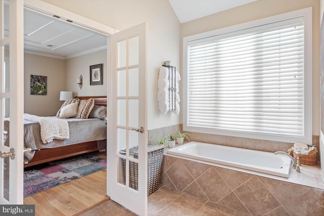 bathroom with tiled tub, ornamental molding, a wealth of natural light, and french doors