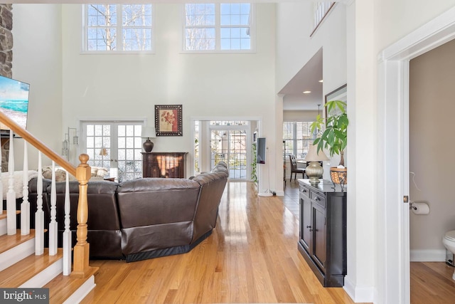 living room featuring french doors, a high ceiling, and light wood-type flooring