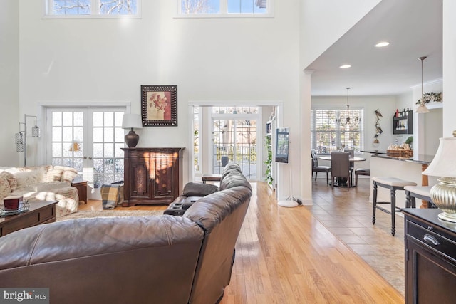 living room featuring french doors, a towering ceiling, and light hardwood / wood-style floors