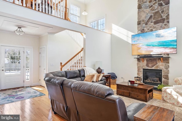 living room featuring plenty of natural light, a towering ceiling, a fireplace, and light hardwood / wood-style flooring