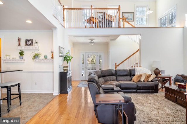 living room featuring a towering ceiling, ornamental molding, and light hardwood / wood-style flooring